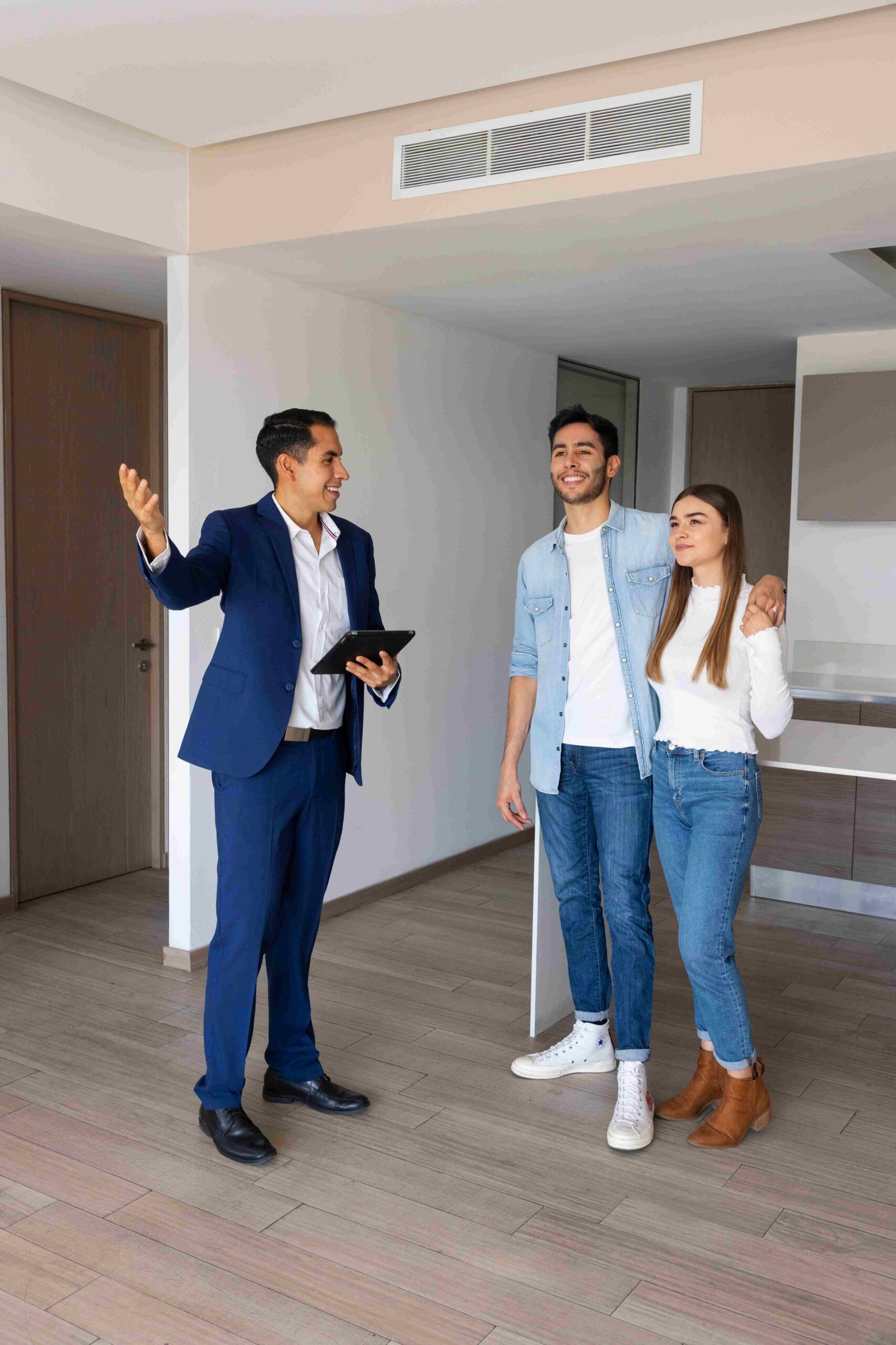 Pareja joven hablando con agente inmobiliario en un departamento nuevo. 