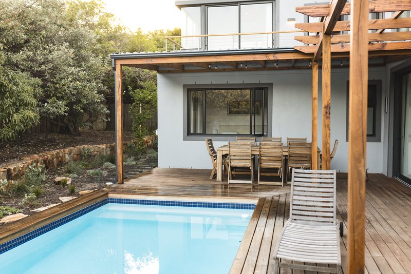 Casa de dos pisos con acabados de madera, un patio y alberca.